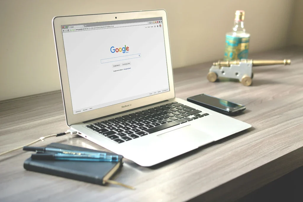 Macbook with books at the top of desk