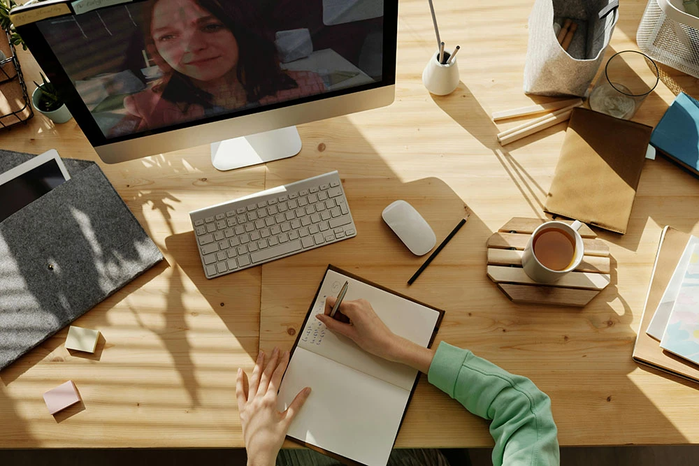 Person writing on a book while watching video
